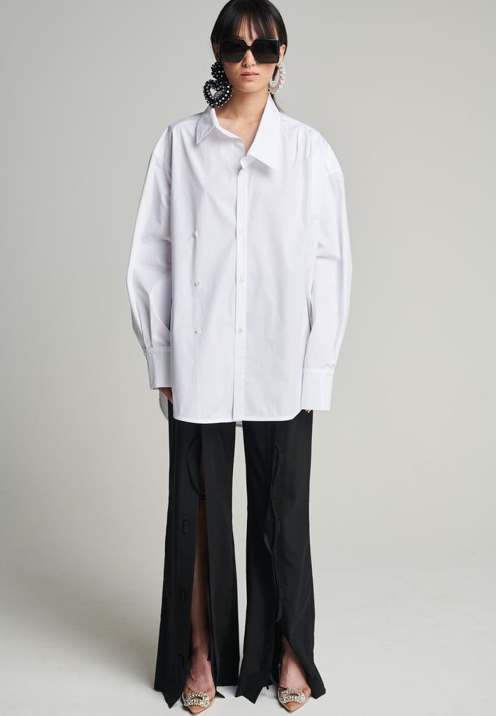 Menswear-inspired wrap-shirt in white. Features a second row of buttons, wear it normally or asymmetrically. 2 in 1. Fits oversize.