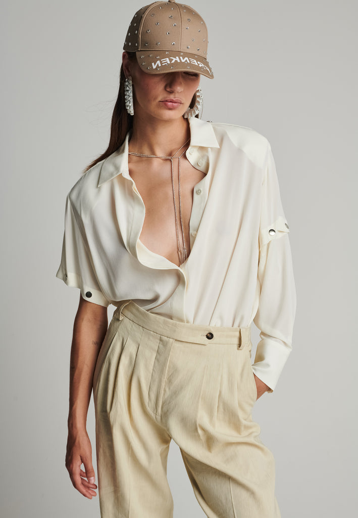 Wide-shouldered silk top in off-white. Features a classic collar, and removable sleeves. Fits oversize.