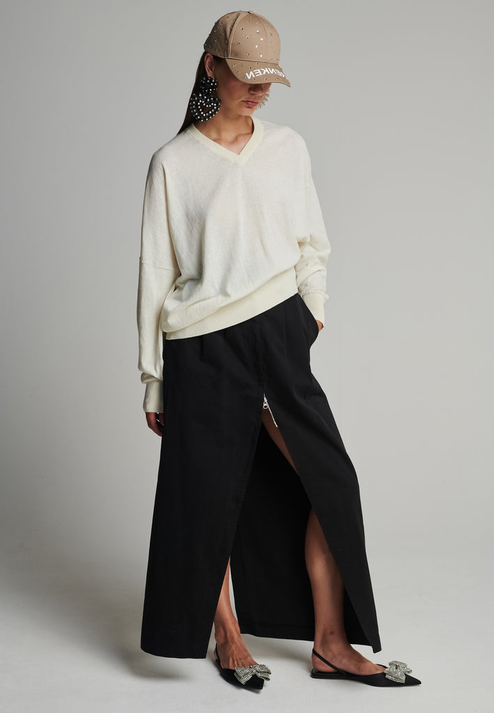 Cotton knitted loose jumper in off-white. Features a v-neck, an asymmetric effect, and wide cuffs. True to size.