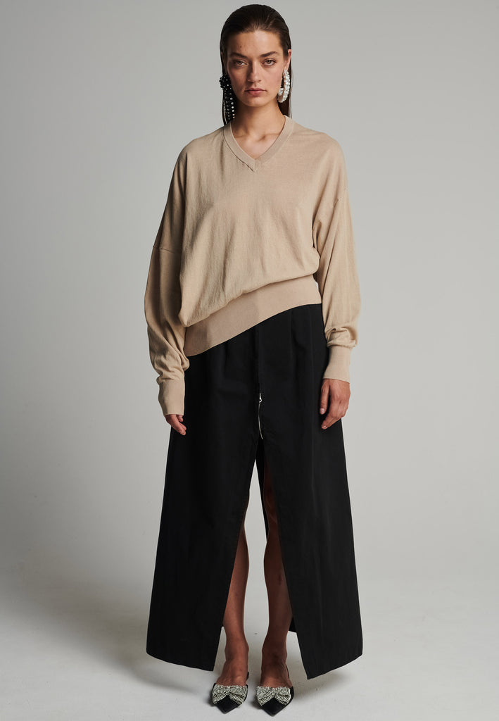 Cotton knitted loose jumper in camel. Features a v-neck, an asymmetric effect, and wide cuffs. True to size.