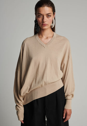 Cotton knitted loose jumper in camel. Features a v-neck, an asymmetric effect, and wide cuffs. True to size.