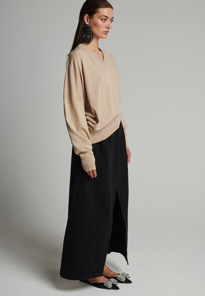 Cotton knitted loose jumper in camel. Features a v-neck, an asymmetric effect, and wide cuffs. True to size.