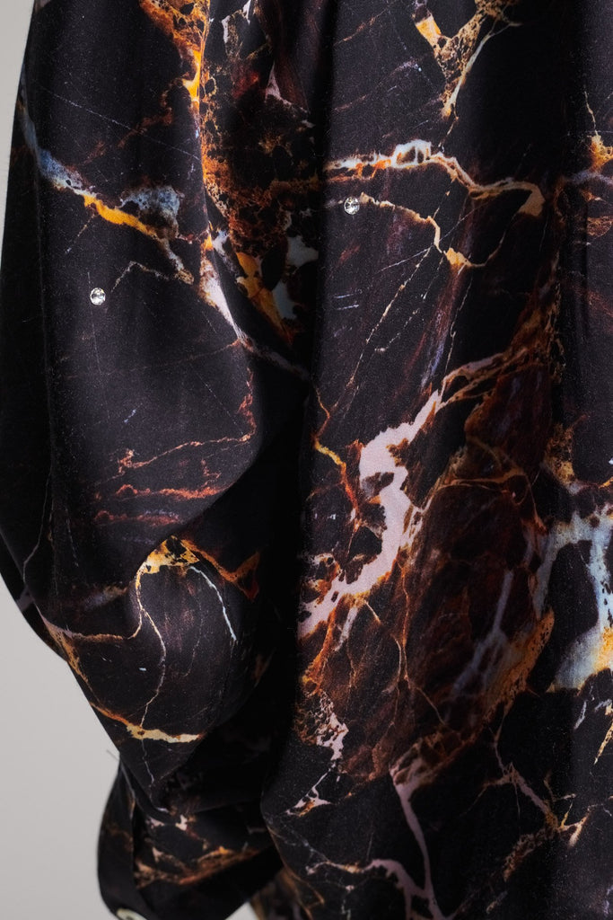 Wide-shouldered shirt with a shiny stretch brown digital marble print. Spiced-up with sprinkled dazzling Swarovski diamonds. Features a button fly-front. Fits oversize.