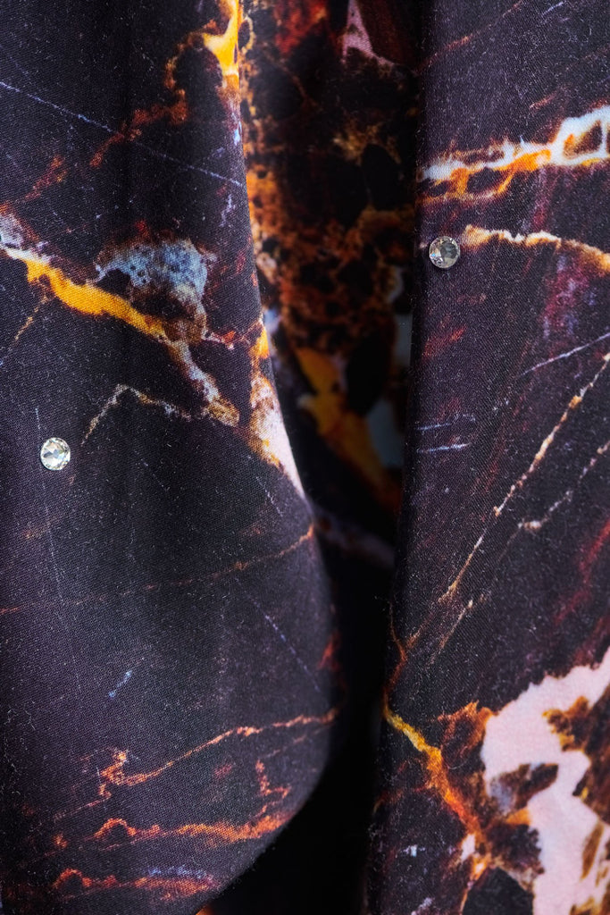Wide-shouldered shirt with a shiny stretch brown digital marble print. Spiced-up with sprinkled dazzling Swarovski diamonds. Features a button fly-front. Fits oversize.