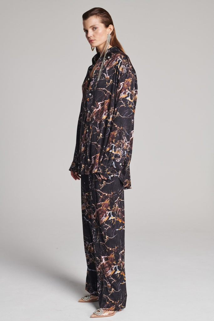 Wide-shouldered shirt with a shiny stretch brown digital marble print. Spiced-up with sprinkled dazzling Swarovski diamonds. Features a button fly-front. Fits oversize.