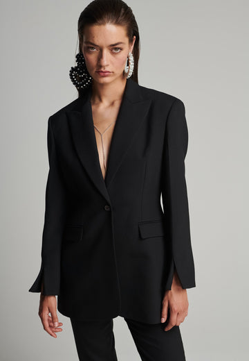 Sharp-tailored blazer in black. Features shoulder-pads, pockets, and cuffs opening. True to size.