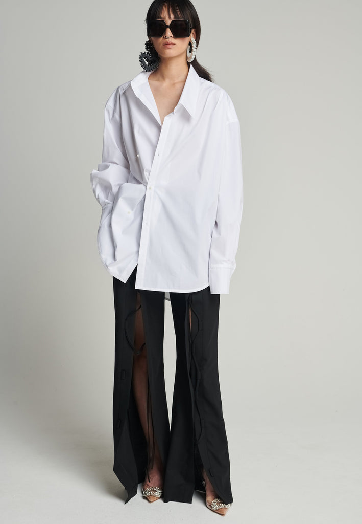 Menswear-inspired asymmetric wrap-shirt. Features two rows of buttons that can be fastened in two different widths. 2 in 1. Pleated on one shoulder. Fits oversize.