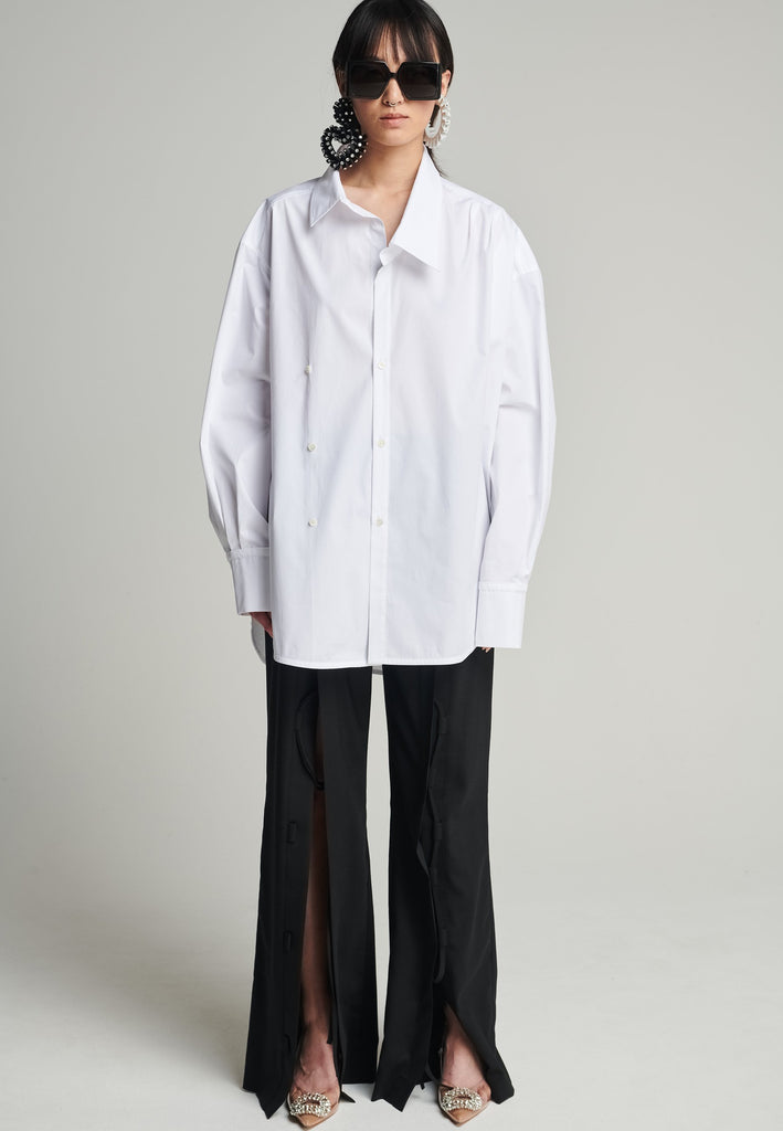 Menswear-inspired asymmetric wrap-shirt. Features two rows of buttons that can be fastened in two different widths. 2 in 1. Pleated on one shoulder. Fits oversize.