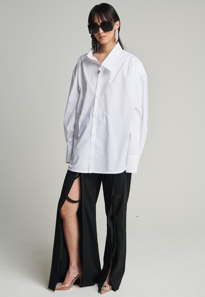 Menswear-inspired asymmetric wrap-shirt. Features two rows of buttons that can be fastened in two different widths. 2 in 1. Pleated on one shoulder. Fits oversize.