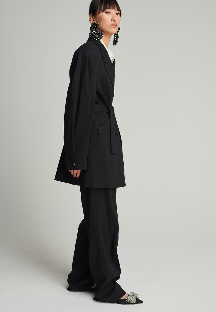 Wide-shouldered blazer in black. Features shoulder-pads, front pockets, and a belt to adjust to your liking. Fits oversize.