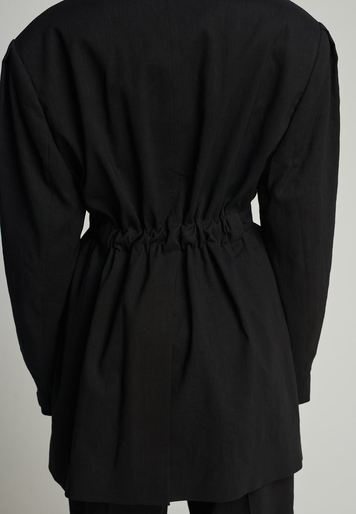 Wide-shouldered blazer in black. Features shoulder-pads, front pockets, and a belt to adjust to your liking. Fits oversize.