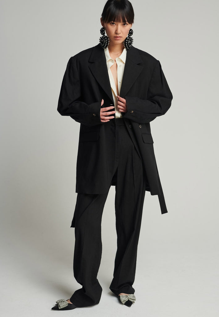 Wide-shouldered blazer in black. Features shoulder-pads, front pockets, and a belt to adjust to your liking. Fits oversize.