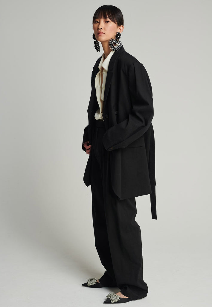 Wide-shouldered blazer in black. Features shoulder-pads, front pockets, and a belt to adjust to your liking. Fits oversize.