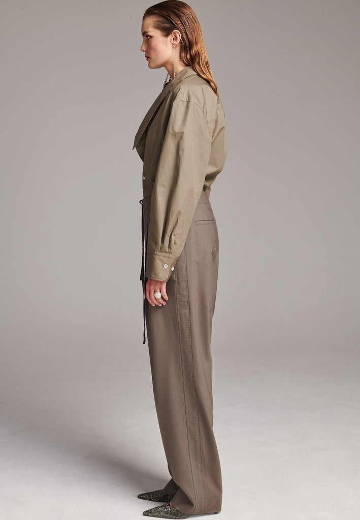 Wide-shouldered asymmetric wrap shirt fitted at the waist. Asymmetric collar structure. Wide relaxed sleeves with multiple buttons on the cuff to adjust the cuff. Wear your cuff small or wide. Detailed with darts at the waist and six-hole buttons. Cut from crispy 100% poplin. Made in Lithuania.
