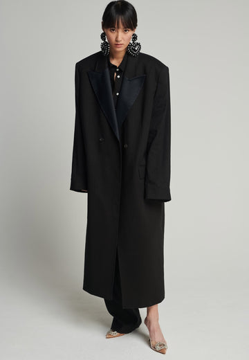 Tuxedo coat in black. Features shoulder-pads, pockets, and exaggerated long sleeves that can be rolled up to reveal a contrasting striped lining. Fits oversize.