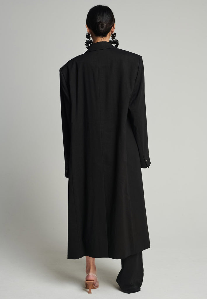 Tuxedo coat in black. Features shoulder-pads, pockets, and exaggerated long sleeves that can be rolled up to reveal a contrasting striped lining. Fits oversize.