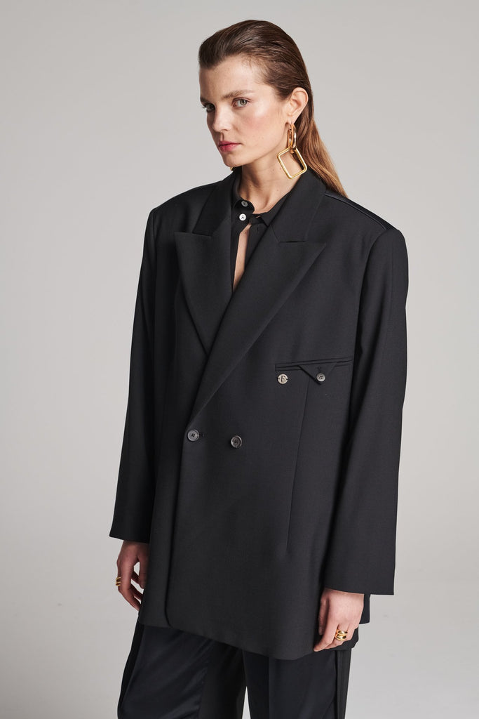 Wide-shouldered blazer in classic wool with an insideout back. Features shoulder pads and a fully lined back. Fits oversized.