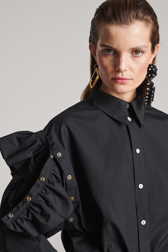 Wide-shouldered shirt with button fly-front. Features a batwing armhole with a detachable shoulder ruffle. Detailed with gold and silver press buttons, use them to separate the shirt's arms. Fits oversize.