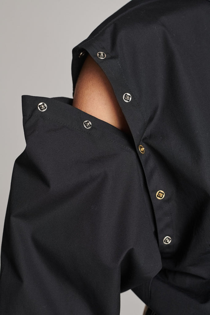 Wide-shouldered shirt with button fly-front. Features a batwing armhole with a detachable shoulder ruffle. Detailed with gold and silver press buttons, use them to separate the shirt's arms. Fits oversize.