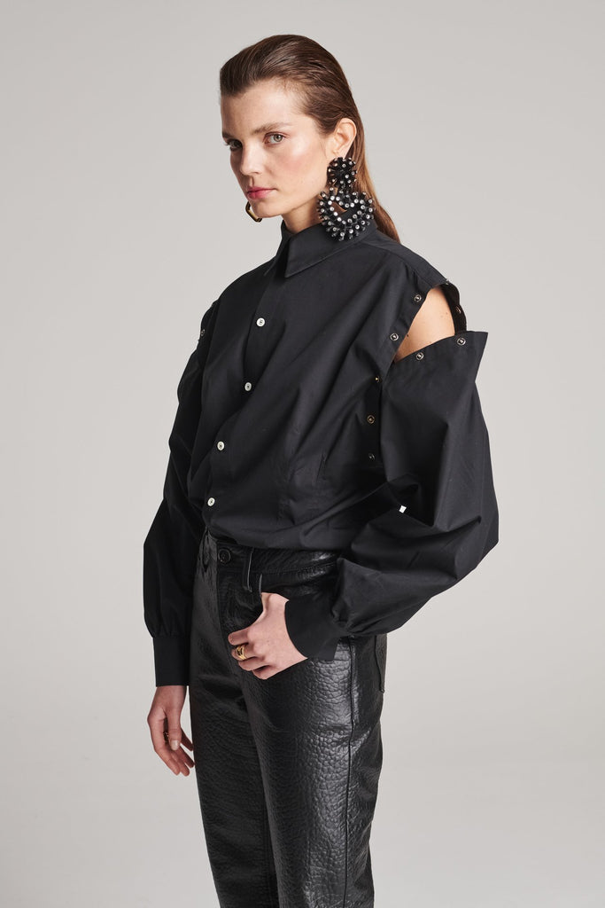 Wide-shouldered shirt with button fly-front. Features a batwing armhole with a detachable shoulder ruffle. Detailed with gold and silver press buttons, use them to separate the shirt's arms. Fits oversize.