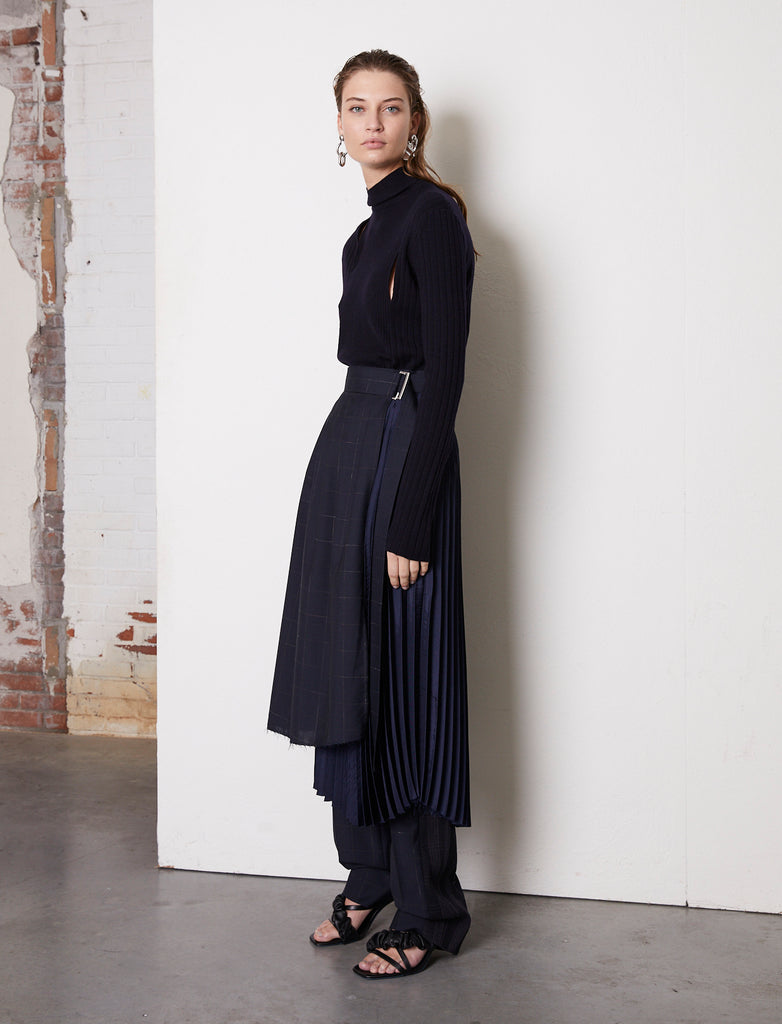 Frenken Asymmetric wrap midi skirt made with two layers mixing wool & satin. This A-line shape skirt is detailed with a pleated soft satin overlayered by a crispy wool shell with a blue windowpane. Crush skirt will wrap around the waistline, closing with a silver buckle, creating an elegant silhouette.