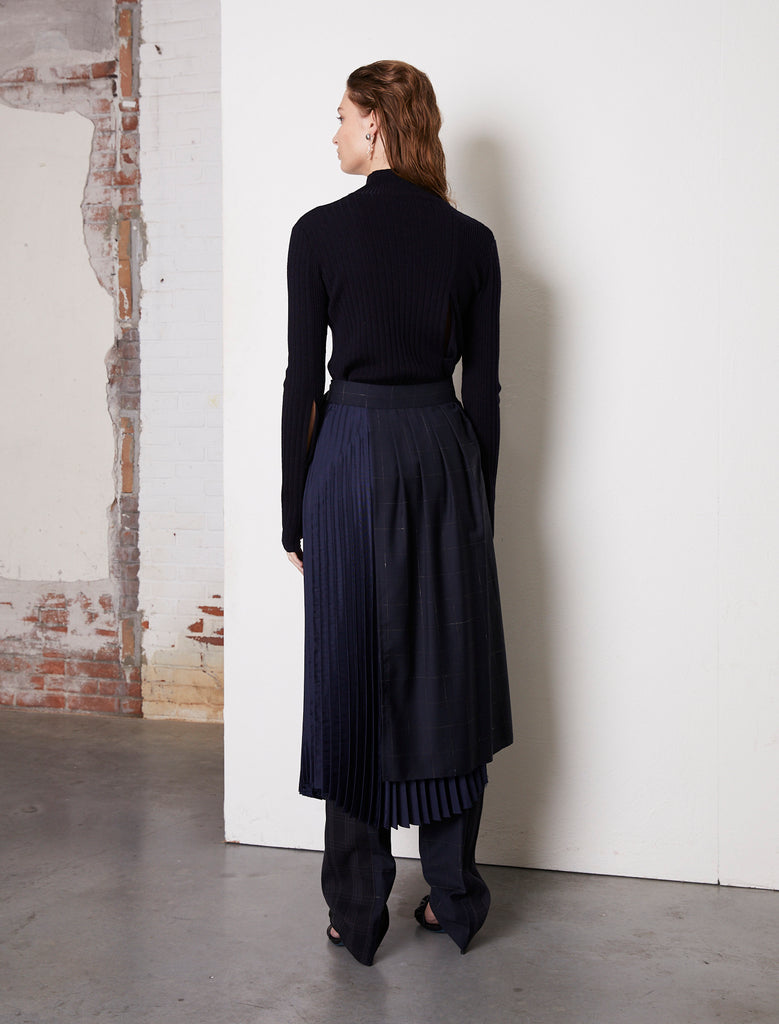 Asymmetric wrap midi skirt made with two layers mixing wool & satin. This A-line shape skirt is detailed with a pleated soft satin overlayered by a crispy wool shell with a blue windowpane. Crush skirt will wrap around the waistline, closing with a silver buckle, creating an elegant silhouette.