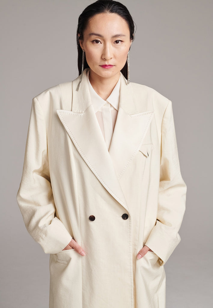 An effortless coat to slip over any outfit, the LONG coat is made from a linen blend with a wrinkle-washed look. Detailed by sharp shoulder pads, double-breast fitting, square hole horn buttons and satin lapel finish with needle stitching. The ankle-grazing length emphasizes the loose fit and the effortless cool over tailoring. FRENKEN makes dressing up every morning easier.