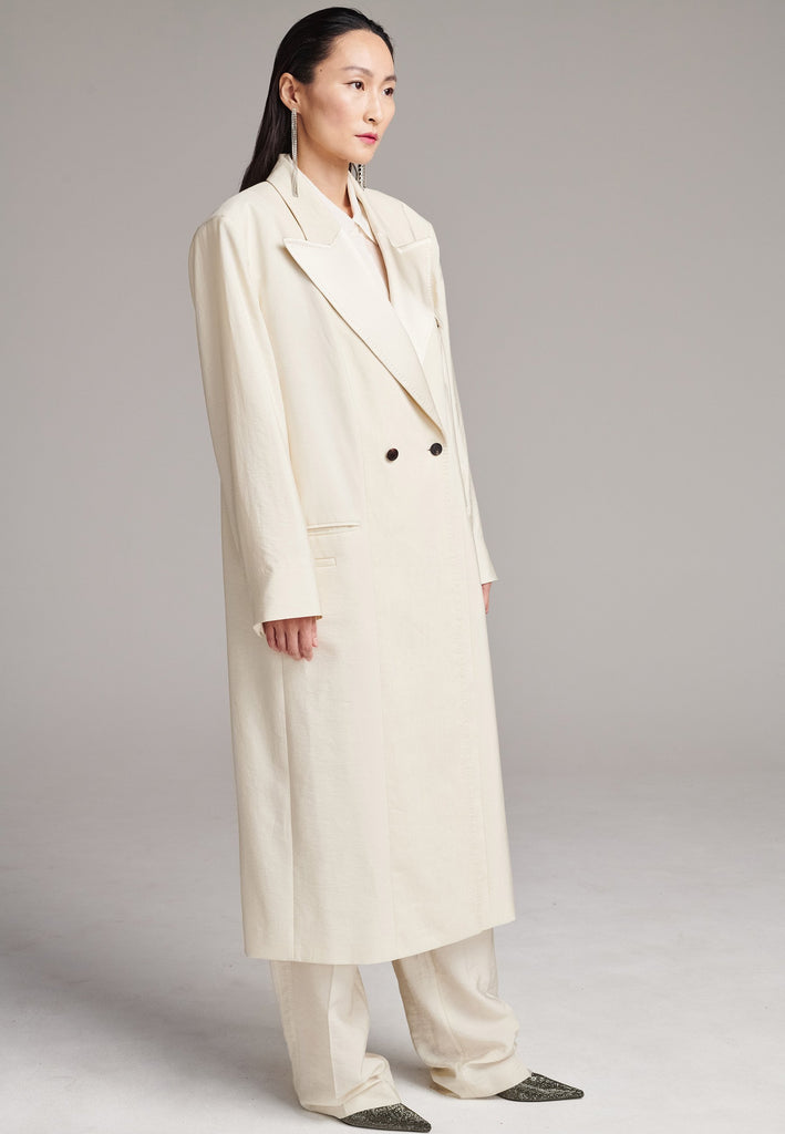 An effortless coat to slip over any outfit, the LONG coat is made from a linen blend with a wrinkle-washed look. Detailed by sharp shoulder pads, double-breast fitting, square hole horn buttons and satin lapel finish with needle stitching. The ankle-grazing length emphasizes the loose fit and the effortless cool over tailoring. FRENKEN makes dressing up every morning easier.