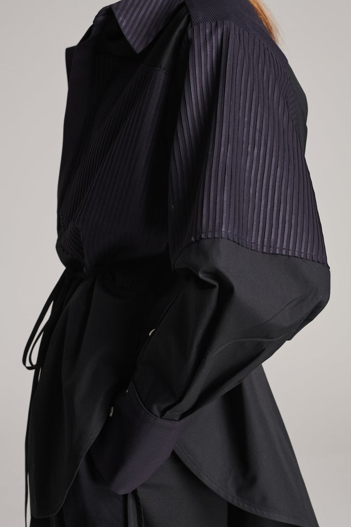 Menswear-inspired shirt. Features plisse details at the top front panel and back. Detailed with a classic collar stand, a concealed button fly-front and a string belt to adjust to your liking. Fits oversize.