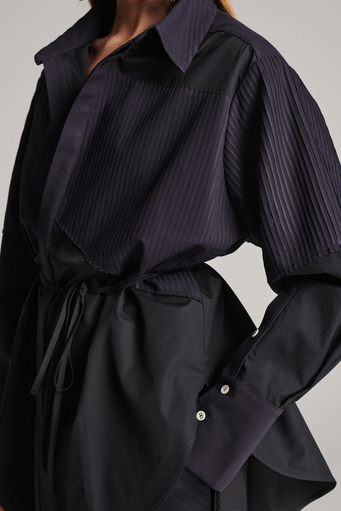 Menswear-inspired shirt. Features plisse details at the top front panel and back. Detailed with a classic collar stand, a concealed button fly-front and a string belt to adjust to your liking. Fits oversize.