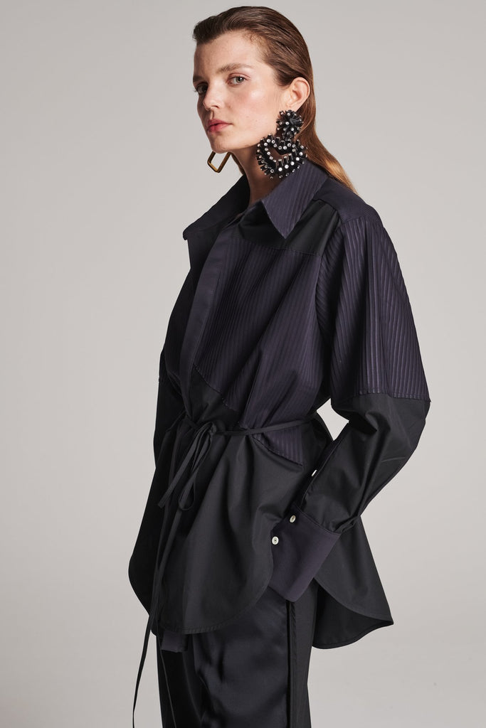 Menswear-inspired shirt. Features plisse details at the top front panel and back. Detailed with a classic collar stand, a concealed button fly-front and a string belt to adjust to your liking. Fits oversize.