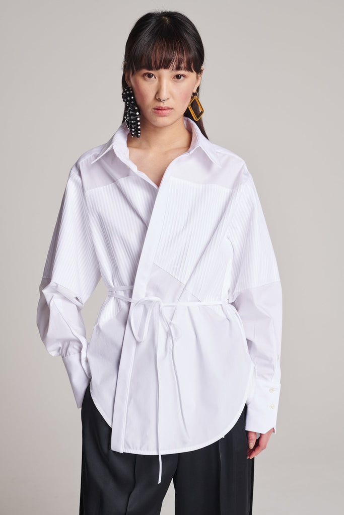Menswear-inspired shirt. Features plisse details at the top front panel and back. Detailed with a classic collar stand, a concealed button fly-front and a string belt to adjust to your liking. Fits oversize.