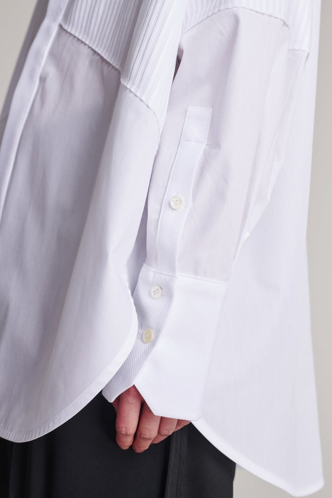 Menswear-inspired shirt. Features plisse details at the top front panel and back. Detailed with a classic collar stand, a concealed button fly-front and a string belt to adjust to your liking. Fits oversize.