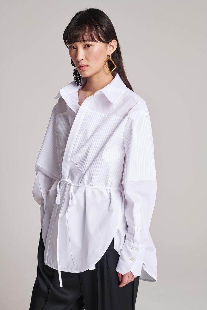 Menswear-inspired shirt. Features plisse details at the top front panel and back. Detailed with a classic collar stand, a concealed button fly-front and a string belt to adjust to your liking. Fits oversize.