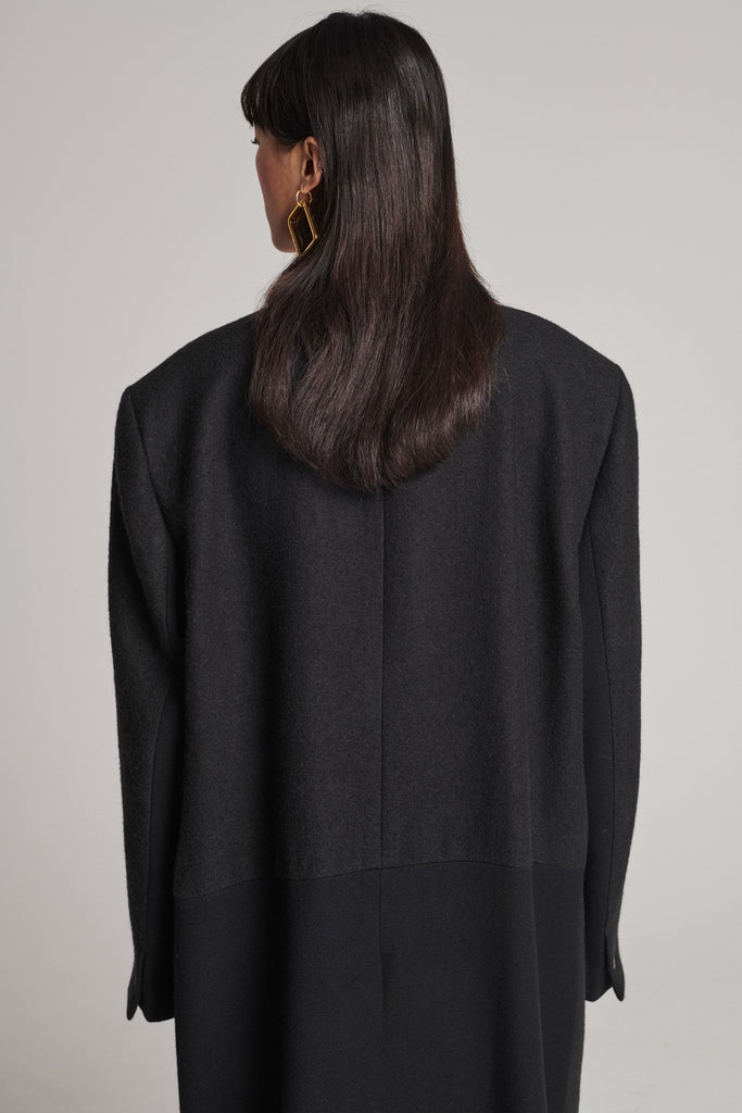 Wide-shouldered coat that combines two fabrics. Features exaggerated long sleeves and pockets. Fits oversized.