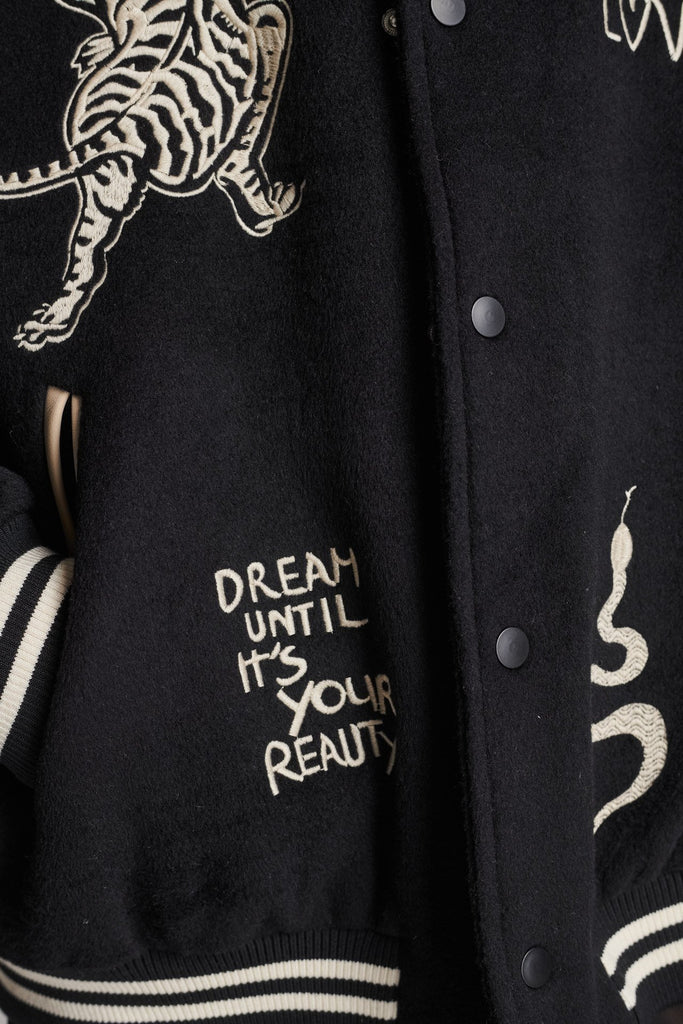 Wide-shouldered baseball jacket. Features unique designs all-over, stamped logo on the back, press buttons, leather shoulder straps, pockets, elasticated cuffs and waistband. Fits oversized.