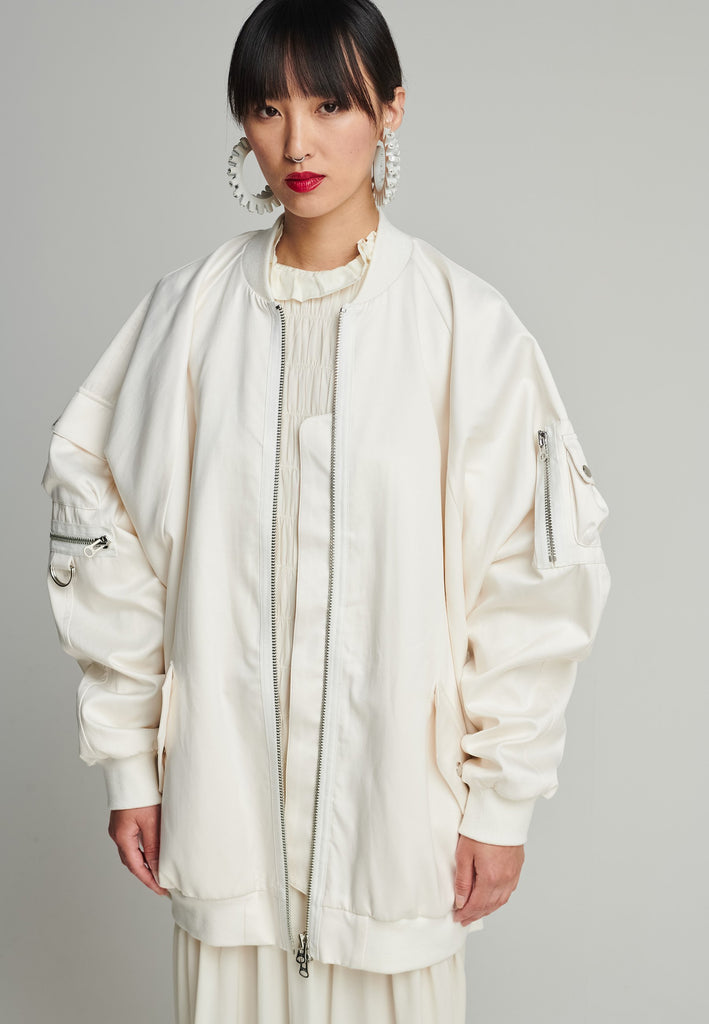 Satin bomber in off-white. Features batwing sleeves, front and arm pockets, zipper closure, and an wrinkled effect on the back. Fits oversize.