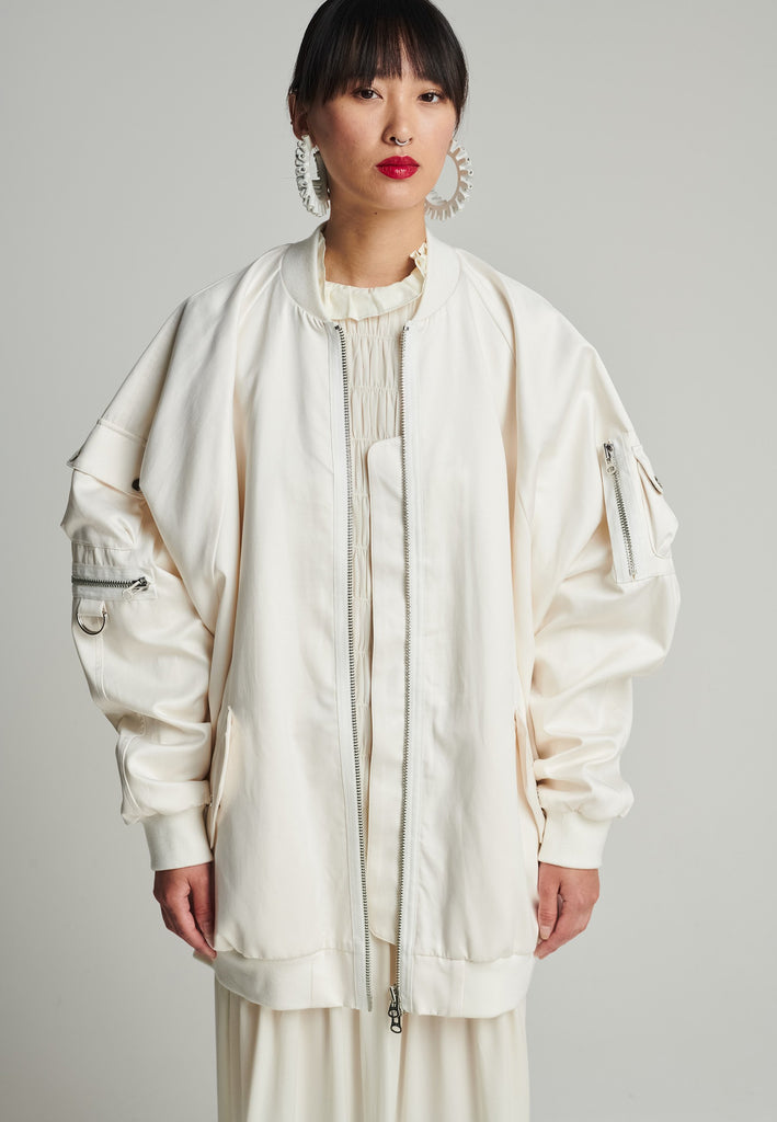 Satin bomber in off-white. Features batwing sleeves, front and arm pockets, zipper closure, and an wrinkled effect on the back. Fits oversize.