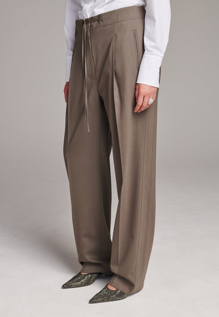 Mid waist wide-leg trousers. Detailed with waisted strings, back pockets and pressed creases.