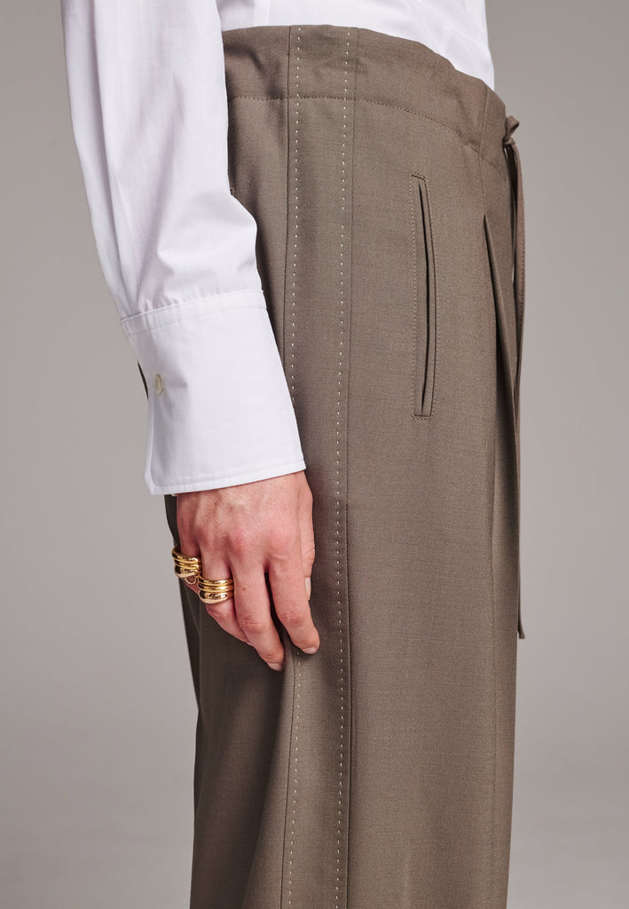 Mid waist wide-leg trousers. Detailed with waisted strings, back pockets and pressed creases.