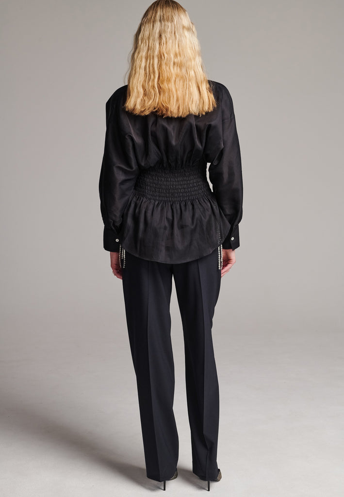 Gathered into a waistline defined by shirring elastic which opens out again into a softly draping peplum hem.