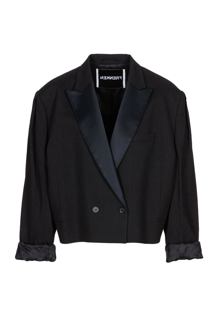Wide-shouldered short blazer in black. Features shoulder-pads, pockets, and exaggerated long sleeves. Fits oversize